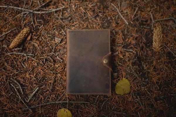 By Kodiak Leather. The Drifter Leather Journal in Dark Walnut is made from Full Grain leather and complete with a snap button closure, this journal is the ultimate gift item for the world traveler or home body. 210 blank pages.Handmade artisan paper. Refillable. Measures 5 x 7 x 2.5 inches.