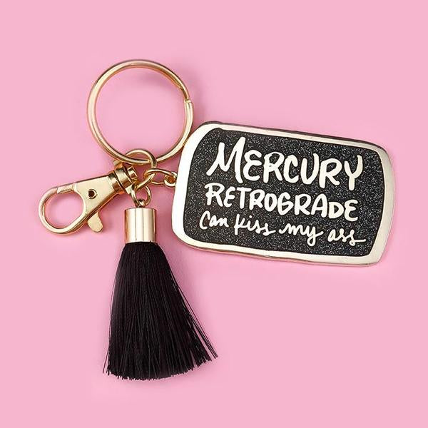 By Little Arrow. Mercury Retrograde Keychain: Cloisonné hard enamel set in 22kt plated gold. Plated gold hardware and adorned with a black silk tassel. Large lobster clasp. Measures 1.25 x 2 inches. Also available in store at FOLD Gallery DTLA.