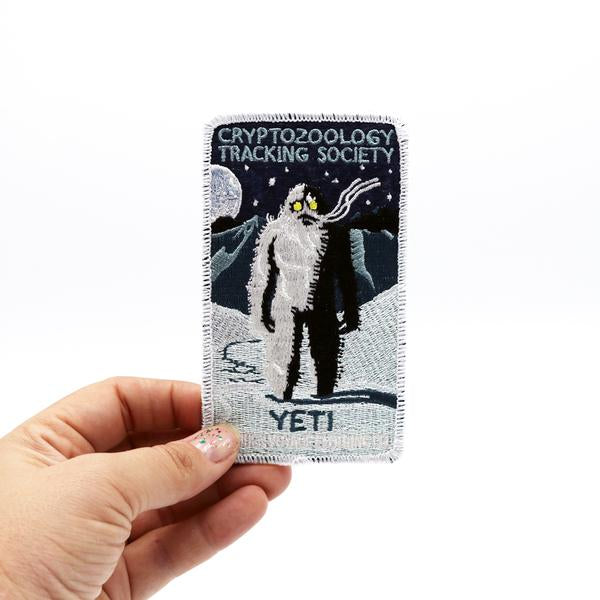 By Maiden Voyage Clothing Co. Yeti Patch. This Cryptozoology Tracking Society patch is reminiscent of the old fashioned National Park patches, but features a cryptid character in their natural habitat! Show your support for the Cyrptozoology Tracking Society! Iron-on (sewing still recommended). Measures 2.5x4.25 inch. FOLD Gallery Dtla.