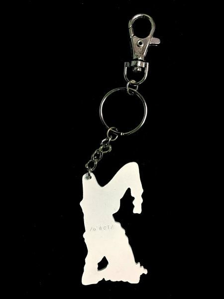 By Adele by Adele Jackson. Out of the Box Girl Keychain. Soft enamel white painted metal keychain with silver chain and closure. Measures 2 1/2 inches. Also available in store at FOLD Gallery DTLA.