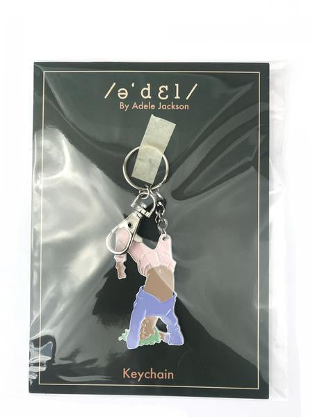 By Adele by Adele Jackson. Out of the Box Girl Keychain. Soft enamel white painted metal keychain with silver chain and closure. Measures 2 1/2 inches. Also available in store at FOLD Gallery DTLA.