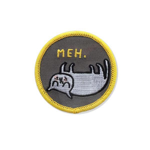 By Badge Bomb. Iron-on Meh Cat Patch by Gemma Correll. Comes packaged in individual hang bag. Measures 2.25 inches. Also available in store at FOLD Gallery DTLA.