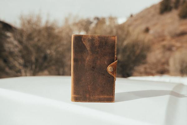 By Kodiak Leather. The Drifter Leather Journal in Antique Brown is the perfect travel companion. Made from Full Grain leather and complete with a snap button closure, this journal is the ultimate gift item for the world traveler or home body. 210 blank pages. Handmade artisan paper. Refillable. 5 x 7 x 2.5 inches.