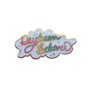 By Little Arrow. Iridescent glitter makes this Daydream Believer Pin totally magical. Cloisonné hard enamel set in 22kt plated gold with dual pins and rubber backs. Measures 2.25 x 1.125 inches.