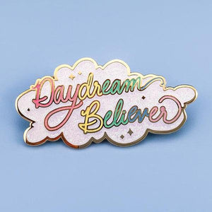 By Little Arrow. Iridescent glitter makes this Daydream Believer Pin totally magical. Cloisonné hard enamel set in 22kt plated gold with dual pins and rubber backs. Measures 2.25 x 1.125 inches.