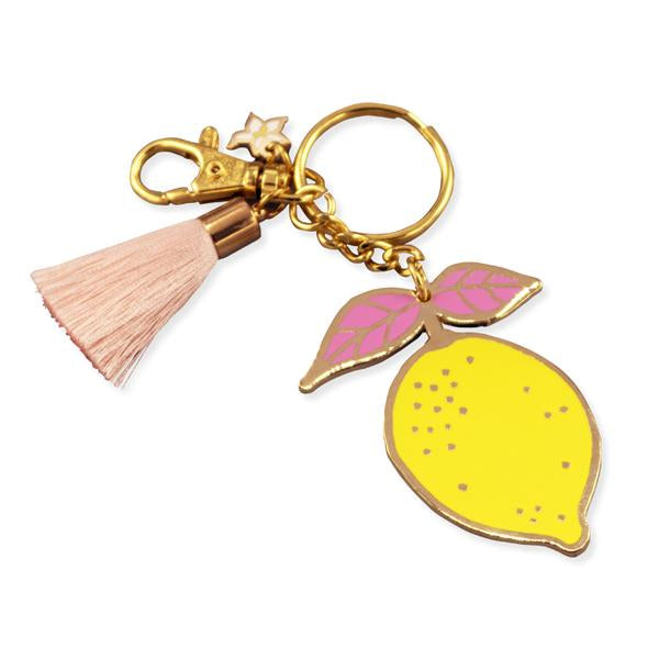 By Little Arrow. Lemon Keychain: Cloisonné hard enamel set in 22kt plated gold. Plated gold hardware and adorned with a silk tassel. Large lobster clasp. Illustrated by Brianna Bulski. Measures 3 x 2 inches. Also available in store at FOLD Gallery DTLA.