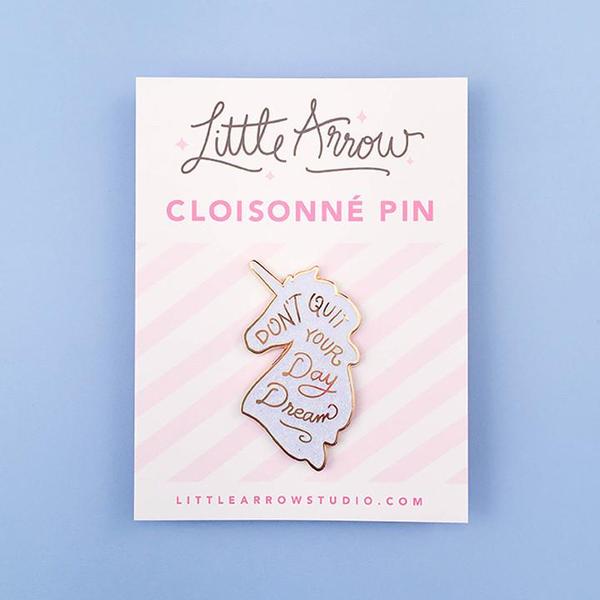 By Little Arrow. Unicorn Daydreams Glitter Pin. Cloisonné hard enamel set in 22kt plated gold. Dual pins with rubber backs. Available in White Iridescent or Pink Iridescent. Measures 1 x 1.75 inches. Also available in store at FOLD Gallery DTLA.