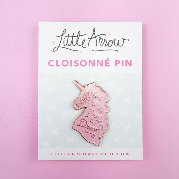By Little Arrow. Unicorn Daydreams Glitter Pin. Cloisonné hard enamel set in 22kt plated gold. Dual pins with rubber backs. Available in White Iridescent or Pink Iridescent. Measures 1 x 1.75 inches. Also available in store at FOLD Gallery DTLA.