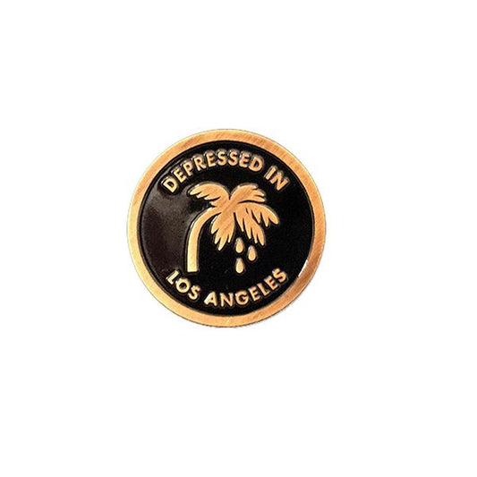 by Little Friends of Printmaking. Depressed in Los Angeles Pin with an antique gold finish and soft black enamel. It's thick! Measures 1 inch round.
