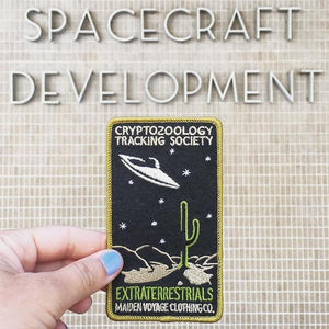 By Maiden Voyage Clothing Co. This Extraterrestrials Patch is reminiscent of the old fashioned National Park patches, but features a cryptid character in their natural habitat! Show your support for the Cyrptozoology Tracking Society! Iron-on (sewing still recommended). Measures 2.5"w x 4.25"h.