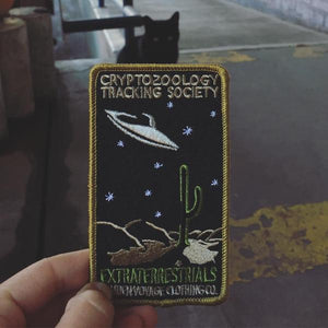 By Maiden Voyage Clothing Co. This Extraterrestrials Patch is reminiscent of the old fashioned National Park patches, but features a cryptid character in their natural habitat! Show your support for the Cyrptozoology Tracking Society! Iron-on (sewing still recommended). Measures 2.5"w x 4.25"h.