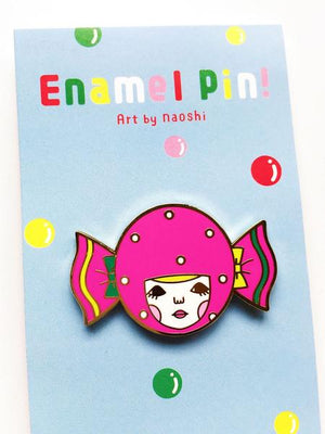 By Naoshi. Candy Girl Pin features: Hard enamel finish. Shiny gold metal plating. 2 posts and gold pin backs to hold securely in place. Packaged with a backing card in a plastic sleeve. Measures 1.0 x 1.6 inches. Also available in store at FOLD Gallery in DTLA.