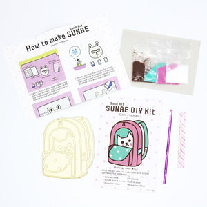By Naoshi. With this Cat in a Rucksack SUNAE DIY Kit, you can make your own fun and easy SUNAE (Sand Art)! Contents of SUNAE DIY Kit: Colored Sand. SUNAE board (Pre-cut). Instructions. Coarse Paper. Toothpick. Wrapping Ribbon. Kit measures 4 x 6 inches. Also available in store at FOLD Gallery in DTLA.