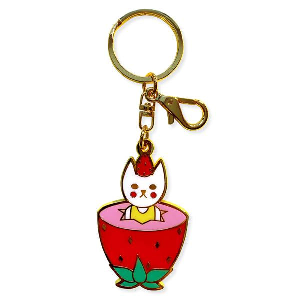 By Naoshi. Strawberry Cat Keychain. Hard enamel plus gold metal keychain. Comes on a backing card in a plastic sleeve. The Strawberry Cat measures 2.2 x 1.4 inches.