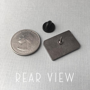 By Rather Keen. Hard enamel Book Nerd Pin. Bright red enamel and black metal with black rubber clasp. “When in doubt, go to the library.” —Hermione Granger. Measures 1 inch wide. Also available in store at FOLD Gallery.