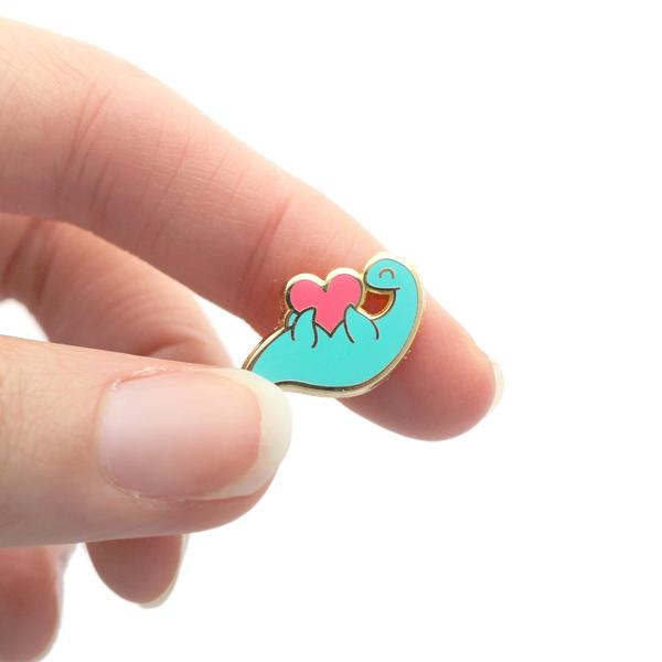 by SHOAL. This Tiny Plesiosaur Pin is guaranteed to steal your heart! One hard enamel pin. Shiny gold metal. One rubber pin back. "OH PLESIOSAUR" stamped on reverse. Measures 0.75-inch (19mm). Also available in store at FOLD Gallery DTLA.