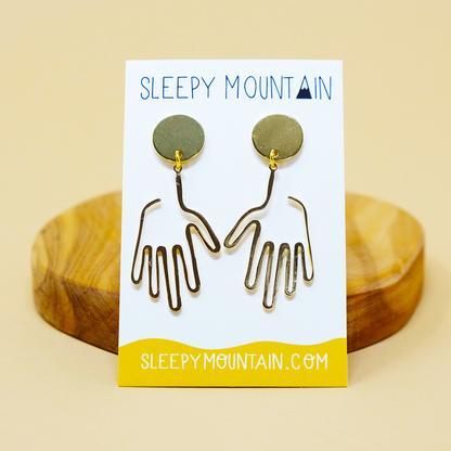 By Sleepy Mountain. Hand Dangle Earrings: Light weight and comfortable. 14k gold plated brass. Care: Store away from moisture and other jewelry to avoid scratching or tarnish. Wipe clean with microfiber cloth. Measures: Overall size 1.75 inches Hand size 1.3 inches.