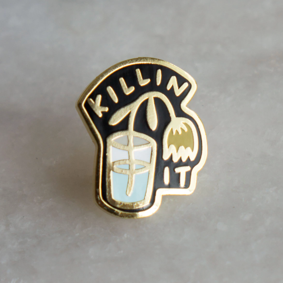 By Stay Home Club. Killin' It Pin details: Gold metal and hard enamel. Comes with a metal locking pinback so it'll stay on your stuff real good! Measures 1"x.75". Please note that due to everyone’s monitor displaying differently, the colors you see may vary.