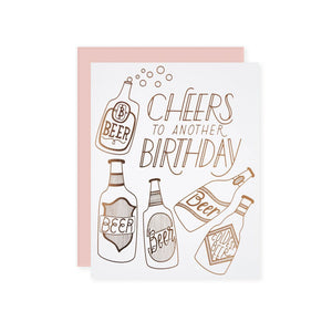 by The Good Twin. Cheers to Another Birthday Card details: Three color screen print on French Paper. Packed in a cello sleeve with corresponding envelope. Blank inside. Made in the USA. Size A2, 4.25 by 5.5 inches folded. Please note that due to everyone’s monitor displaying differently, the colors you see may vary.