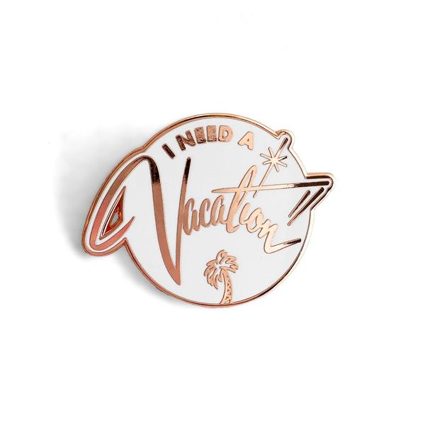 by World Famous Original. White hard enamel I Need a Vacation Pin with rose gold finish and rubber clasp. Measures 1.25 inches. Also available in store at FOLD Gallery DTLA.